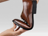 Anatomic & Co Fata - laced Tan leather formal shoe held and bent to relay flexibility against a grey background
