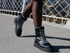 Bagatt D31-AO137 5000 - Black boots worn by a person on a street with a metal fence in the background