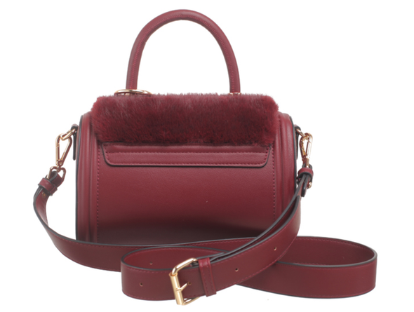 Bessie London Plush Barrel handbag in burgundy with faux fur detail and a wide cross body strap on a white background, back view