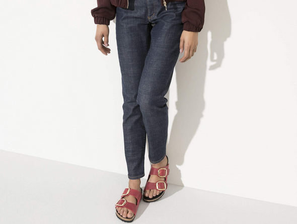 Birkenstock Arizona Big Buckle 1020163 - Fire Red double strap sandal with large gold buckles and a cork footbed with a black sole worn with dark blue jeans on a white background