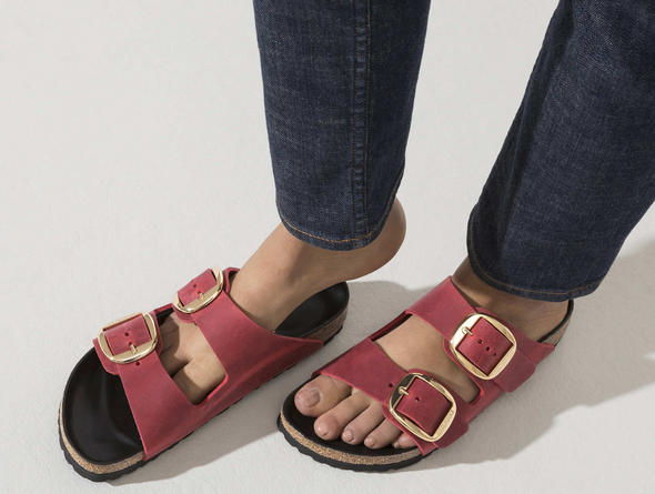 Birkenstock Arizona Big Buckle 1020163 - Fire Red double strap sandal with large gold buckles and a cork footbed with a black sole worn with dark blue jeans on a white background