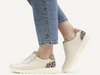 Caprice 9-23751-45 199 - Off White Combi laced sneaker with side zip, with an animal print panel at the heel worn by a lady in blue jeans on a grey background.