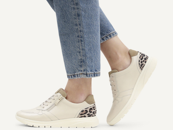 Caprice 9-23751-45 199 - Off White Combi laced sneaker with side zip, with an animal print panel at the heel worn by a lady in blue jeans on a grey background.