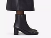 Clarks Fernie Zip - Black leather ankle boot with block heel worn with a long black skirt on a white background