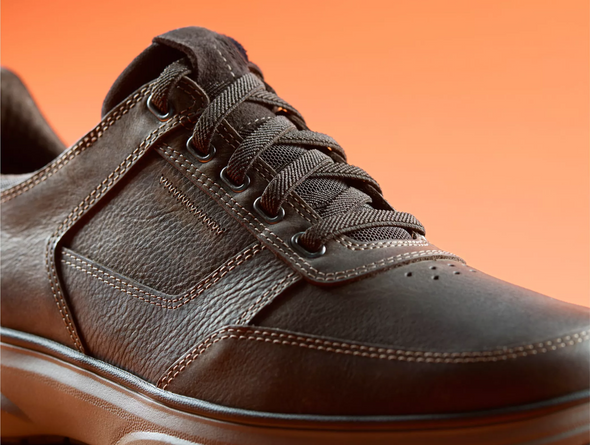Clarks Mullan Easy - Dark Brown leather laced casual shoe close up against an orange  background