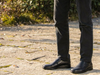 Person wearing G-Comfort A-905 - Black slip on shoe and pants standing on a paved surface with greenery in the background