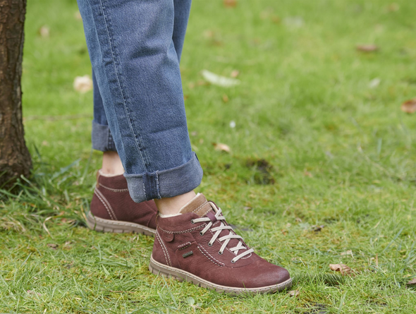 Josef Seibel Steffi 53 93153 410 - fur lined laced ankle boot in Bordeaux worn with rolled up jeans on grass on a white background. 