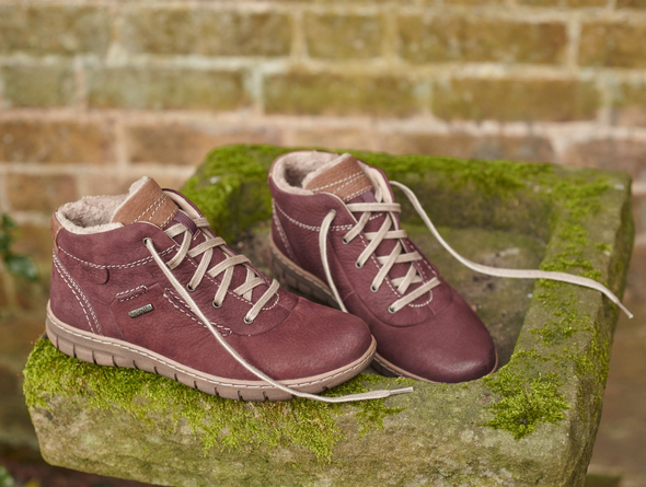 Josef Seibel Steffi 53 93153 410 - fur lined laced ankle boot in Bordeaux on a mossy slab against a red brick wall. 