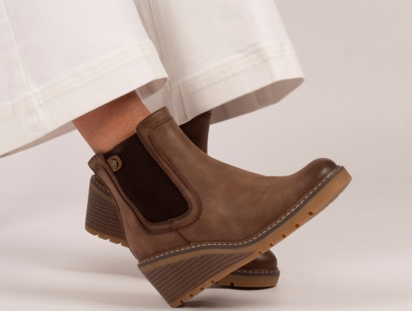Lotus Connie GLC014 - Brown wedge ankle boot with elastic panels worh with white wide leg trousers against a natural background.