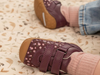 Close-up of a baby wearing Startrite Little Smile 0823-18 - Burgundy floral baby shoes with Velcro straps and a rubber sole on a soft surface